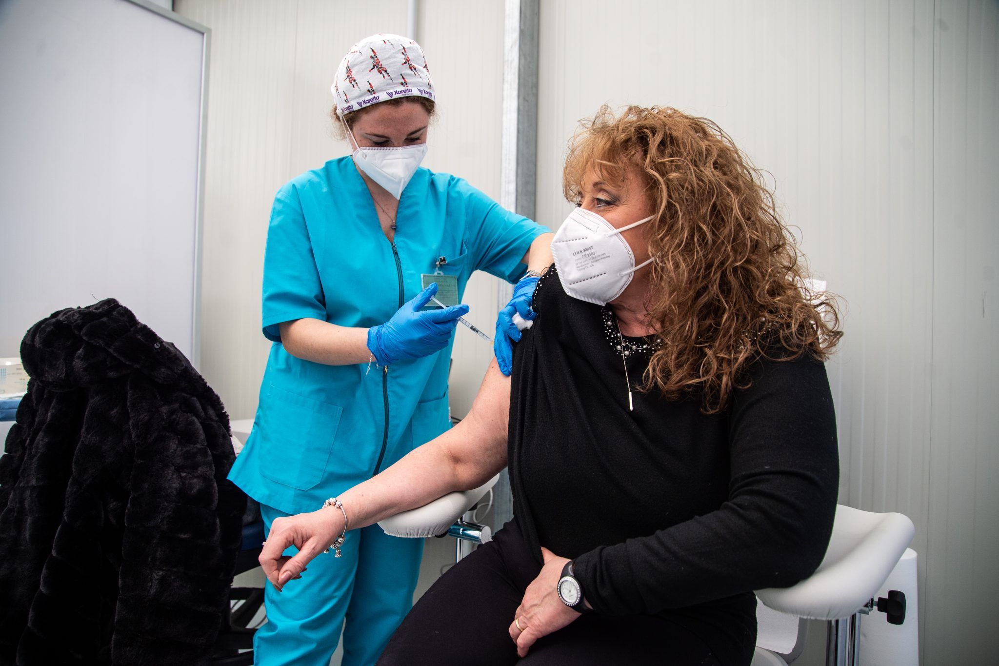 A woman being vaccinated by a health care worker