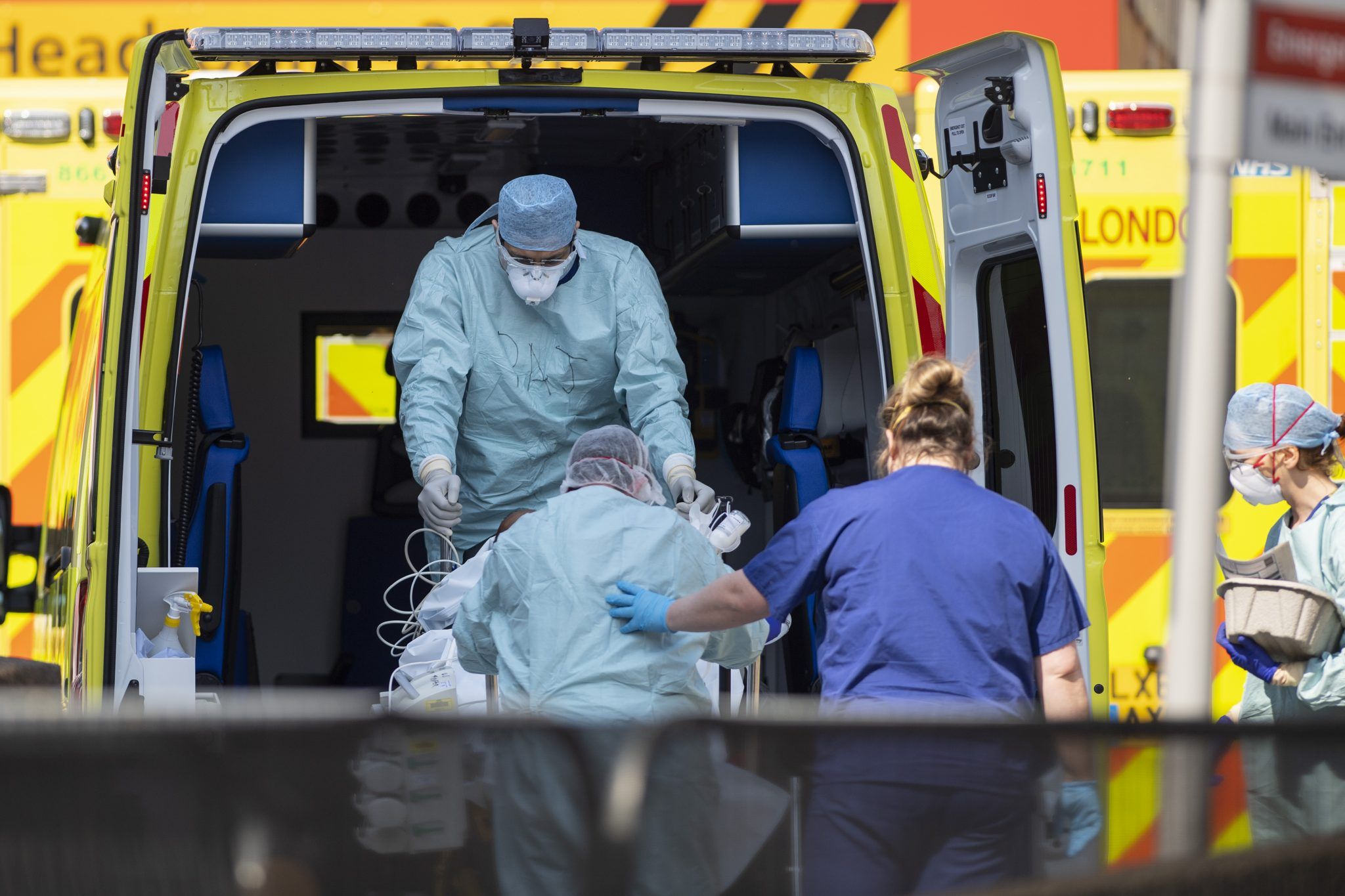 کارگران بیمارستان در PPE بیمار Covid را به داخل آمبولانس می برند