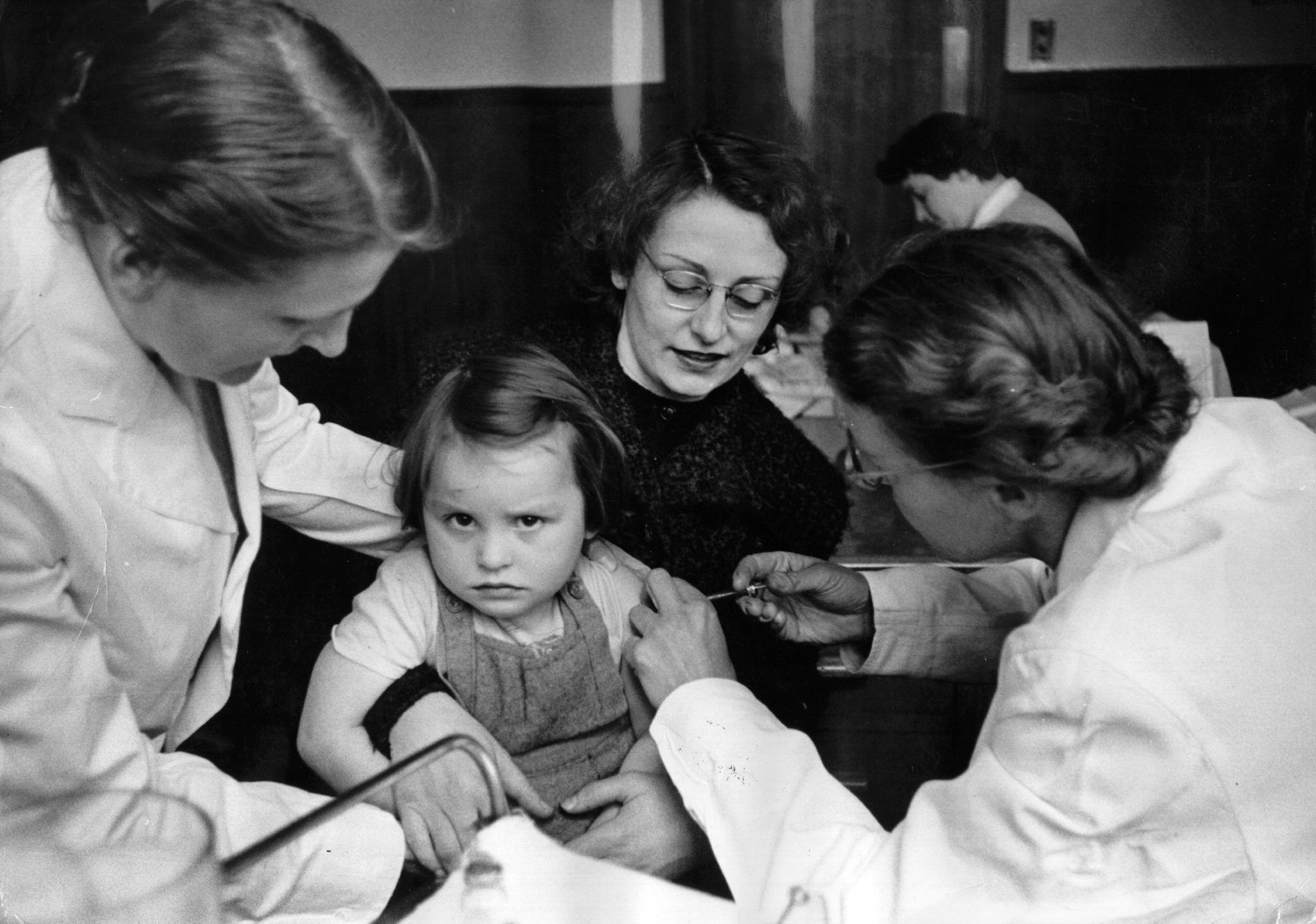 A rather reluctant-looking girl is given an injection of vaccine against poliomyelitis as part of Britain's biggest vaccination programme. Original Publication: Picture Post - 8399 - A Mass Experiment - pub. 1956 (Photo by Thurston Hopkins/Getty Images)