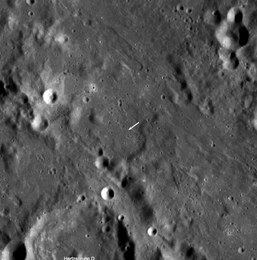 The crater formed (5.226 degrees north, 234.486 degrees east, 1,863 meters elevation) in a complex area where the impact of ejecta from the Orientale basin event overlies the degraded northeast rim of Hertzsprung basin (536 kilometers diameter). The new crater is not visible in this view, but its location is indicated by the white arrow. LROC WAC mosaic, 110 kilometers width. (Credits: NASA/Goddard/Arizona State University)